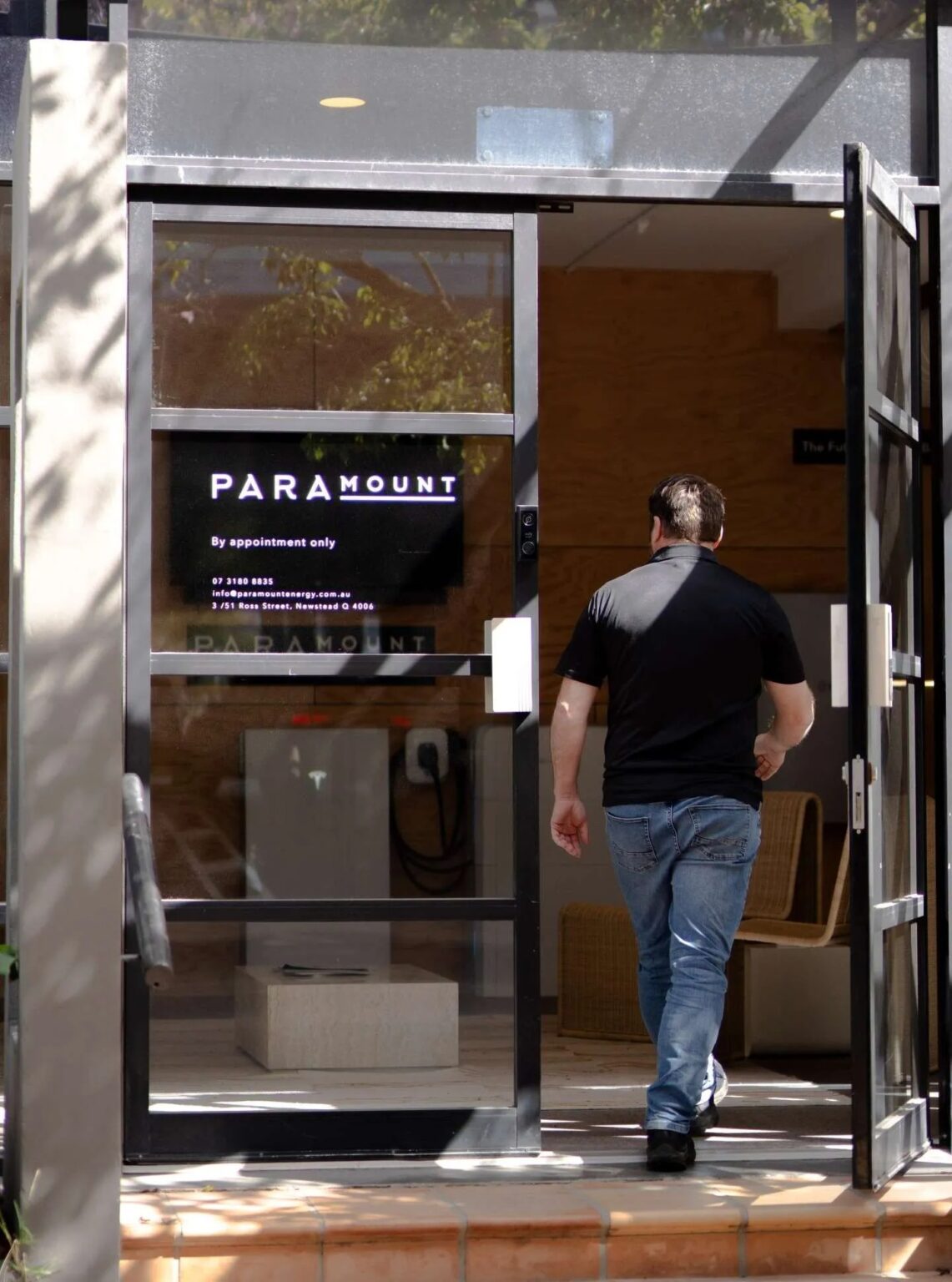 A man entering the glass entrance of Paramount therapy clinic in Newstead, with appointment-only signage visible on the window.